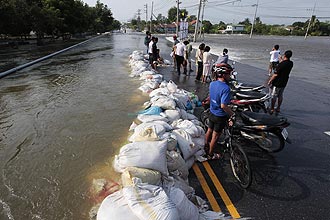 Residents stand along a flooded street in Thailand's Lopburi province